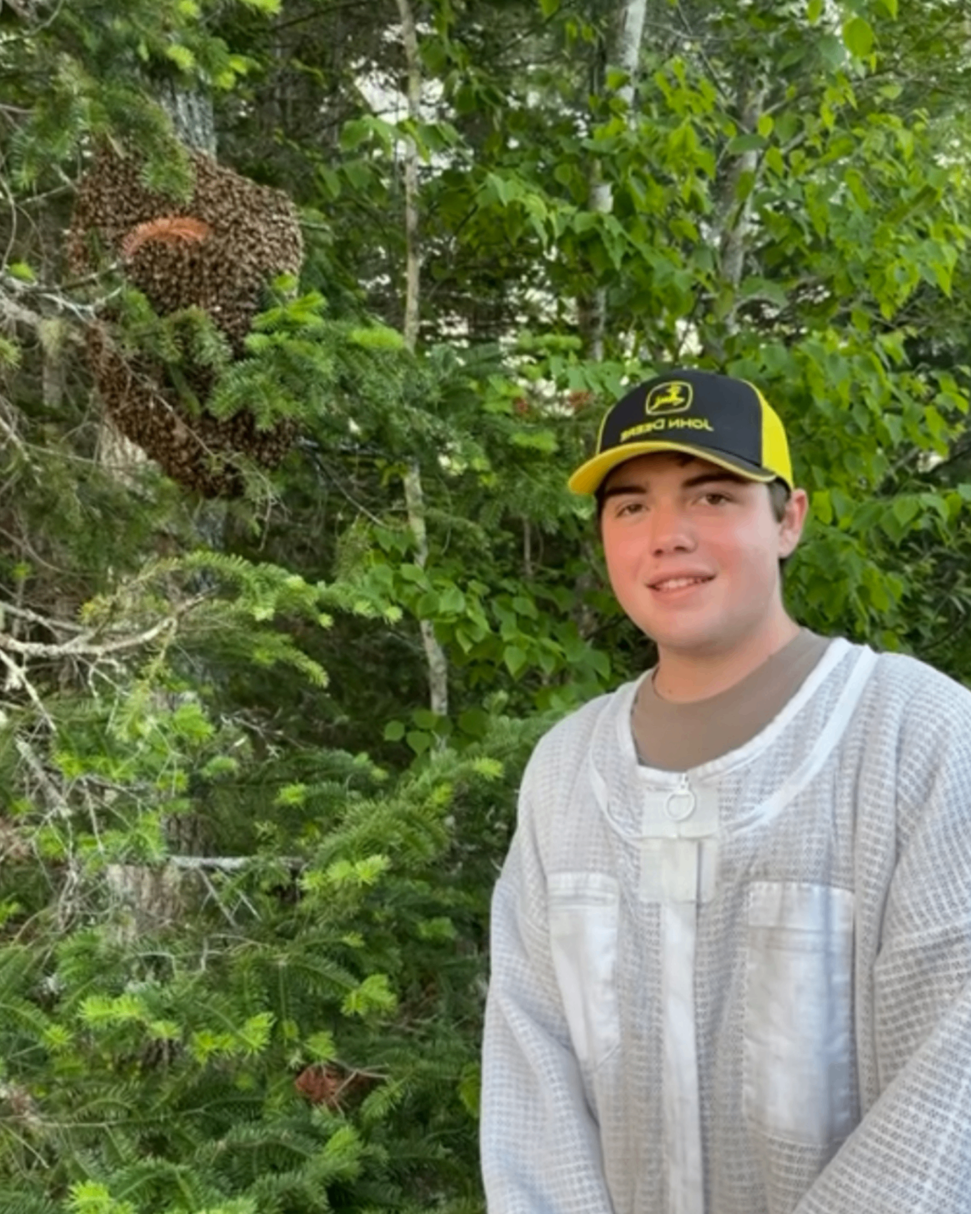 Hunter Carnley in beekeeping gear next to a wild bee swarm in a Florida forest
